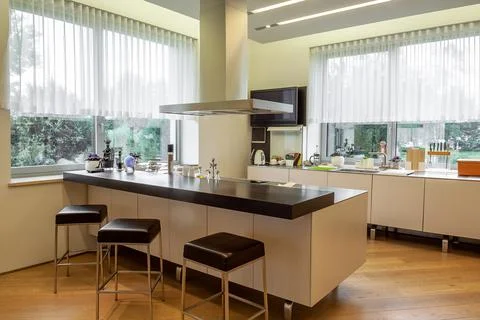 Modern kitchen interior with wide windows, functional furniture and appliances Stock Photos