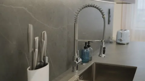 Modern kitchen with marble backsplash featuring stainless steel sink Stock Footage 271199399