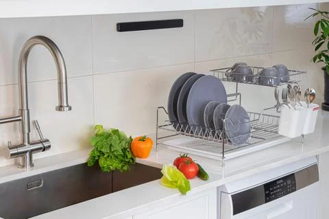 Modern kitchen with multiple dishes, fresh fruit, and vegetables near a sink Stockfoto's