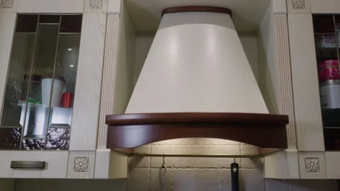 Modern kitchen range hood with cream shade, wood trim, sleek design Stock Footage 336746309