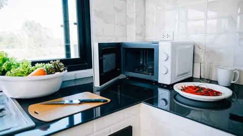 A modern kitchen setting showcasing an open microwave oven door Stock Photos