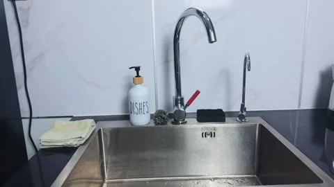 Modern kitchen sink area showcasing a clean stainless steel basin, elegant Stock Footage 341862347