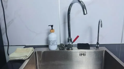 Modern kitchen sink featuring chrome faucet, dish soap dispenser, steel scrubber Stock Footage 341862434