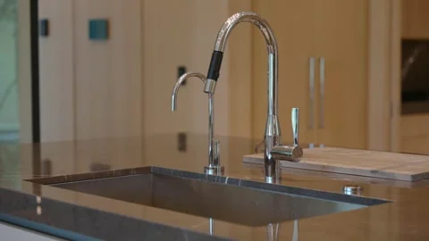 Modern kitchen sink with sleek chrome faucet. Faucet has high arc and separate Stock Footage 297751799