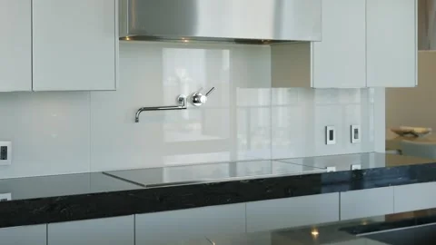 Modern kitchen with sleek design. Black countertop, white cabinets and stainless Stock Footage 294853759