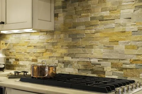 Modern Kitchen With Stone Backsplash And Copper Pot On The Stovetop. Stock Photos