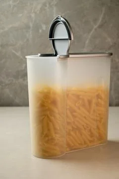 Modern kitchen storage container holding penne pasta on a countertop Stock Photos