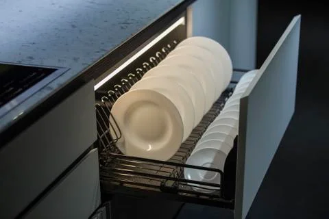 Modern kitchen, storage space for plates, illuminated drawer in luxury kitche Stock Photos