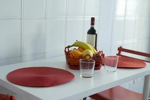 Modern kitchen table set for two with fruit bowl and wine bottle 库存照片