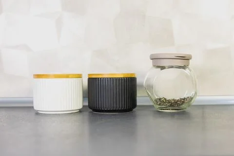 Modern kitchen tea boxes in white, black, and glass on a dark countertop. Stock Photos