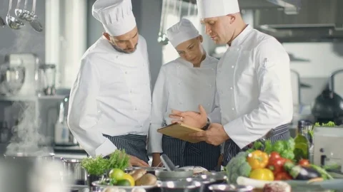 In the Modern Kitchen Team of Cooks Use Tablet Computer For Recipes, They Smile Stock Footage
