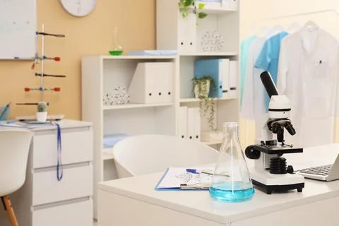 Modern laboratory interior with a microscope flask with blue liquid and lab c Фото
