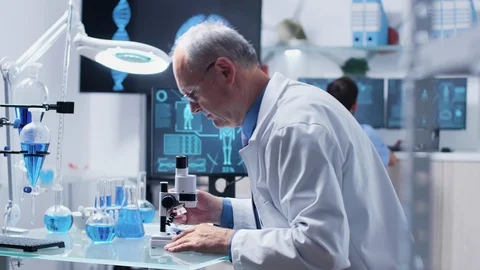 In modern laboratory scientist is looking at samples through a microscope Video stock 111007569