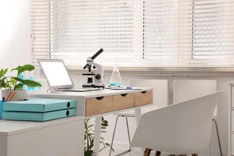 Modern laboratory workspace with microscope, laptop, and scientific equipment Фото