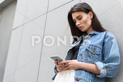 Modern lady chatting on her smartphone outdoors Stock Photos
