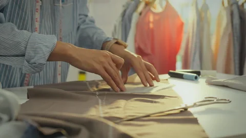 A modern lady at her work table marks fabric, preparing to cut along the lin Stock Footage 281688402