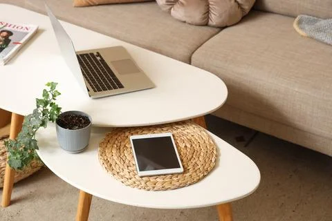 Modern laptop and tablet computer on coffee table in living room, closeup Stock Photos