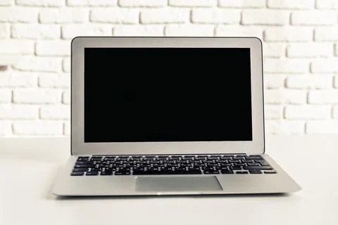 Modern laptop on a clean workspace with a white brick wall background during Stock Photos