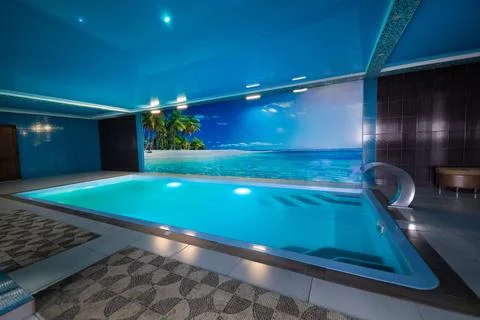 A modern large indoor pool with blue lighting and a waterfall. Stock Photos