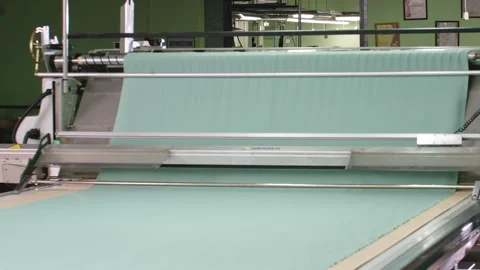 Modern laying complex at sewing factory - cutting light-colored plain fabric Stock Footage 313807428