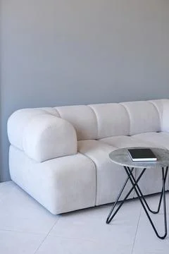 Modern light gray sofa with rounded edges and soft upholstery, accompanied by a Photos