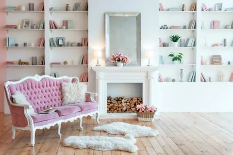 Modern light interior with fireplace, spring flowers and cozy pink sofa 库存照片