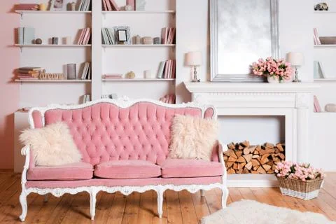Modern light interior with fireplace, spring flowers and cozy pink sofa Stock Photos