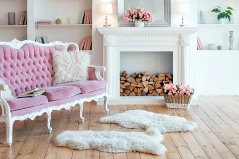 Modern light interior with fireplace, spring flowers and cozy pink sofa Stock Photos