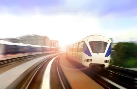 Modern light rail train on the move with bright sunlight glare Stock Photos