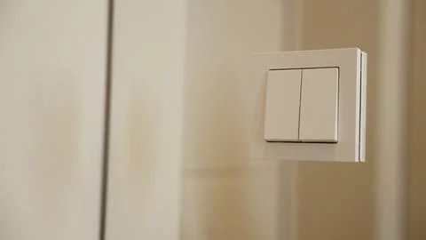 Modern light switch mounted on a white wall. Stock Photos