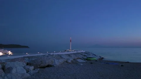 Modern Lighthouse on Rock Pier at Blue Hour with Distant Mountain Silhouette Vídeo Stock 341679867