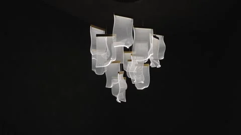 Modern lighting fixture made of white fabric like elements hangs and gently Vidéo 335198735