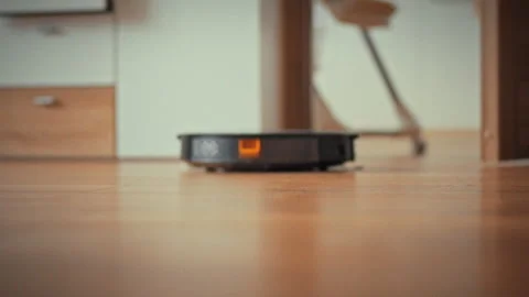 In a modern living room an autonomous robot vacuum cleaner uses AI-driven se Stock Footage 334546267