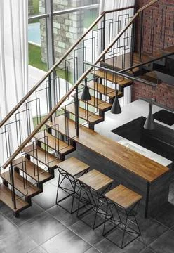 Modern loft kitchen interior with panoramic window and wooden staircase to the Stock Photos