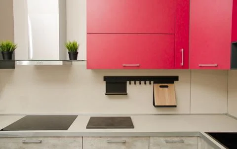 Modern loft-style kitchen with red cabinets, stove, range hood and table with Stock Photos