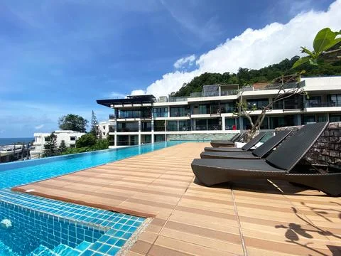 Modern luxury resort with infinity pool and sun loungers overlooking ocean Stock Photos
