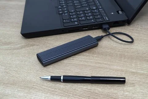 Modern M.2 NVMe SSD External Enclosure Connected to a Laptop on a Wooden Desk Stock Photos