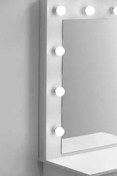 Modern makeup dressing table with mirror and lighting close-up. Stock Photos