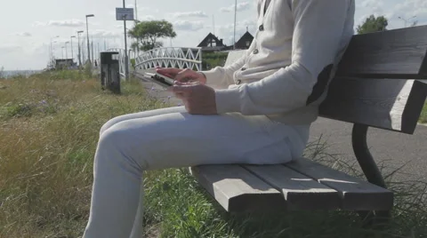 Modern man on a bench that scrolls on a tablet Stock Footage 52517016