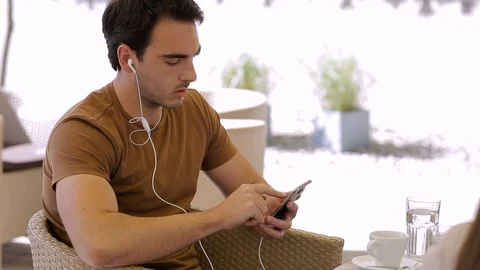 Modern man in caffe typing on his phone with headphones Stock Footage 87391783
