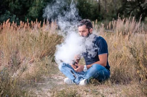 Modern man enjoying an e-cigarette. Man really likes process of smoking. Stock Photos