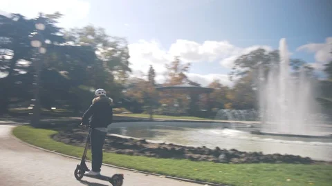 Modern Man with Helmet Using Electric Scooter in sunny Park with Fountain 2 Vidéo 98756951