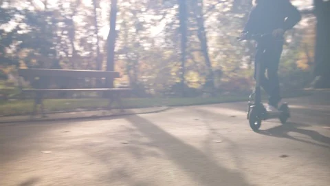 Modern Man with Helmet Using Electric Scooter in Sunny Park 2 Vidéo 98756966