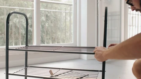 Modern man self assembling metallic shelf oneself home improvement comfortable Stock Footage 233469755