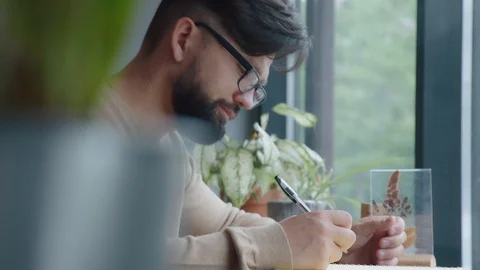Modern man sits at the window in a cafe and writes in an organizer Stock Footage 93560809