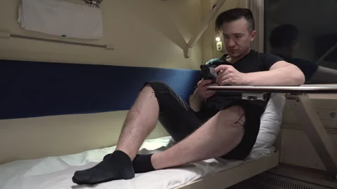 Modern man sitting in train carriage and using smartphone. Concept of travel Stock Footage 264585462