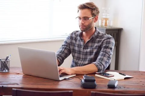 Modern man typing on a laptop while seated at desk Stock Photos
