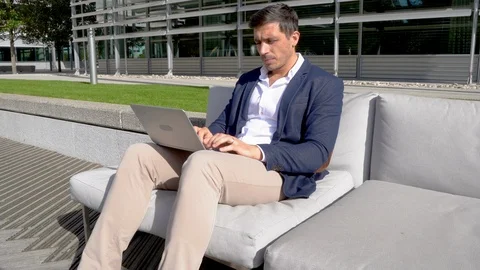Modern man using laptop outside in trendy business park 4K Stock Footage 96058936