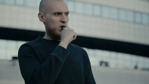 Modern man vaping outside in the warm summer evening Stockbeeldmateriaal 85611667