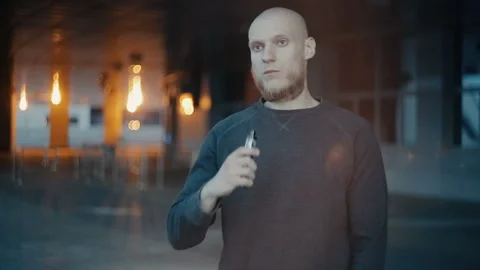 Modern man vaping outside in the warm summer evening Stockbeeldmateriaal 85612005